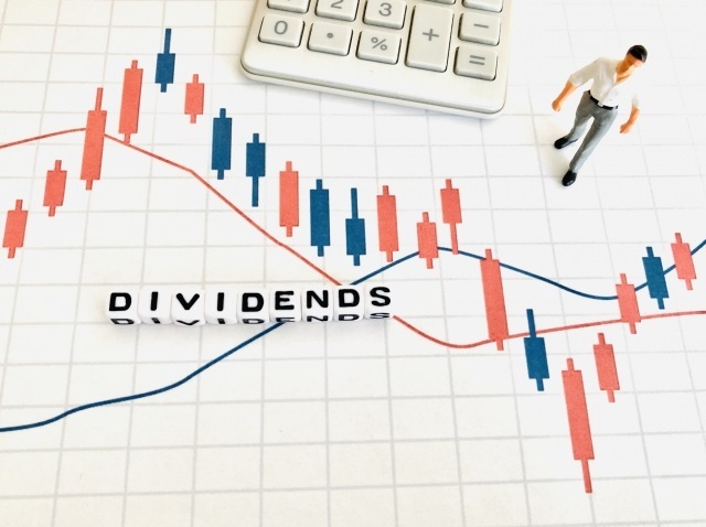 DIVIDENDSの文字と株価チャートと白い電卓
